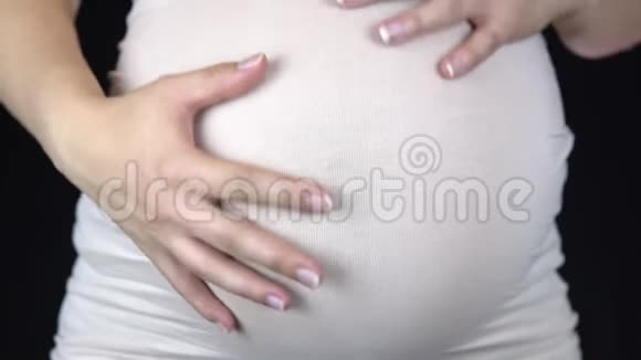 孕妇抚摸着她的胃从手中露出一颗心穿着轻便T恤的女人视频的预览图