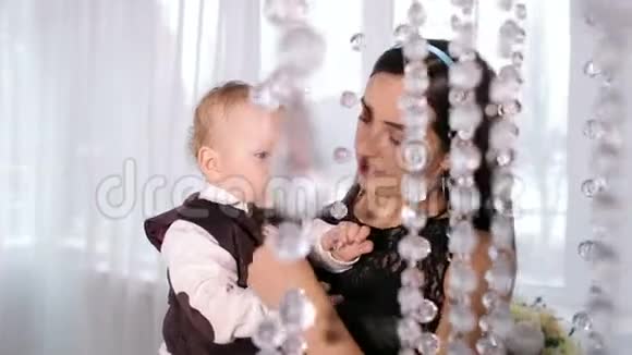 快乐妈妈和她的小儿子在一个明亮的房间里玩里面有漂亮的吊灯视频的预览图