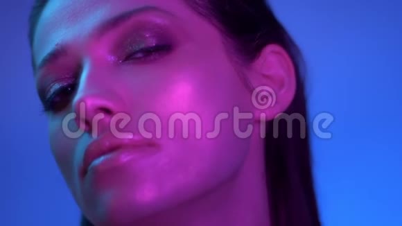时尚模特在紫色霓虹灯的轮廓左转并抬起她的头满意视频的预览图