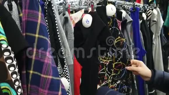 女人在商店里挑选衣服女人在衣架上衣服视频的预览图