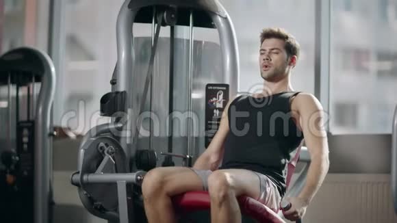 强壮的运动员在健身俱乐部的运动模拟器上做腿部运动视频的预览图