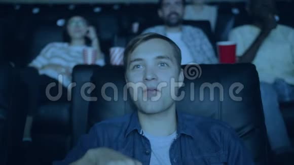 快乐的男人在电影院看电影和吃爆米花的慢动作视频的预览图