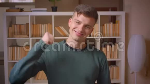 年轻男学生的肖像竖起大拇指表示同意并喜欢在图书馆视频的预览图