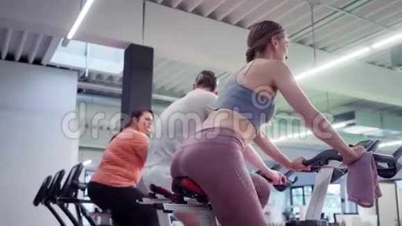 男人和女人在健身房里骑健身自行车视频的预览图