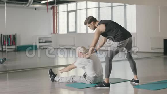 退休老人和健身教练一起做伸展运动视频的预览图