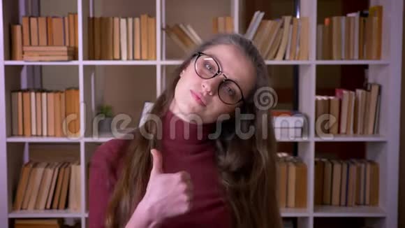 戴着眼镜的年轻白种人女学生的特写照片她竖起大拇指开心地笑着看着镜头视频的预览图