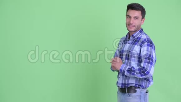 快乐年轻的西班牙裔男子向背后展示一些东西视频的预览图