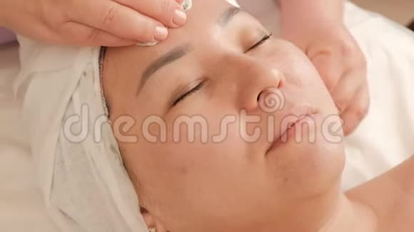 美容师在美容院清洗一名亚洲中年妇女的面部皮肤女孩的化妆程序复兴视频的预览图