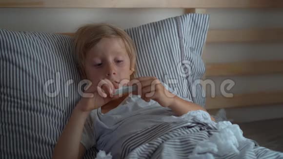 一个小男孩看着温度计对他的体温感到高兴流感康复的概念视频的预览图