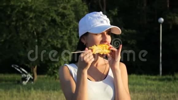 美丽的黑发女人吃玉米看着镜头视频的预览图
