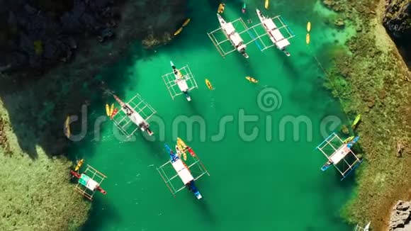空中无人驾驶飞机观看皮艇和船只围绕着一个美丽的热带泻湖周围是垂直的石灰石悬崖视频的预览图