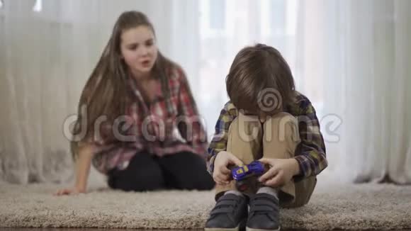 画像上的姐姐骂弟弟弟弟正坐在松软的地毯上玩玩具车视频的预览图