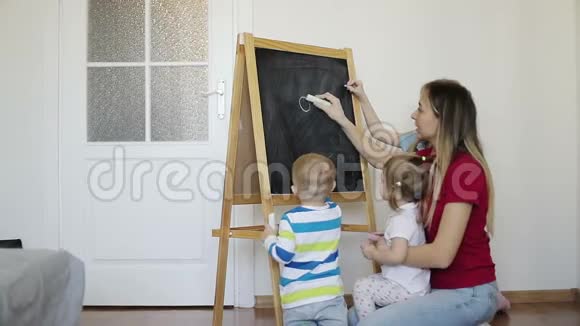 幸福的家庭在家里用蜡笔在黑板上画画视频的预览图