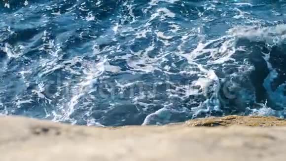 海水缓慢流动海滩上的岩石上有白色泡沫破裂视频的预览图