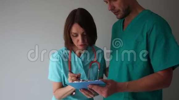 女医生在年轻实习生手中的文件夹中签名医生和实习生医疗助理视频的预览图