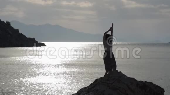 那个优雅的女孩在日落时分在海面上的一块岩石上缓慢地跳舞视频的预览图