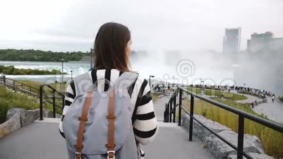 镜头跟随旅游妇女背着背包在著名的尼亚加拉大瀑布慢动作向拥挤的观景台走去视频的预览图