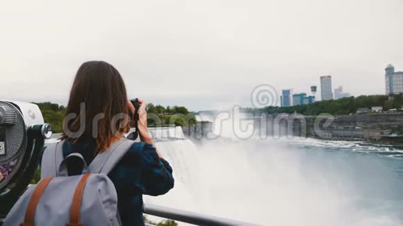 后景的快乐旅行者妇女与背包和相机拍照惊人的尼亚加拉瀑布慢动作视频的预览图