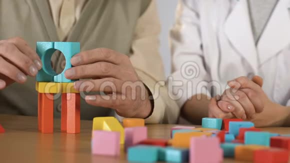 爷爷用颤抖的双手制作木制立方体的房子康复中心视频的预览图