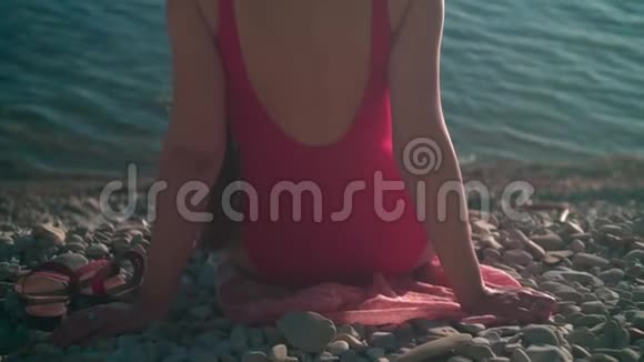 一个穿着红色一件泳衣的漂亮女孩坐在夕阳下的海滨那个女孩坐在相框里视频的预览图