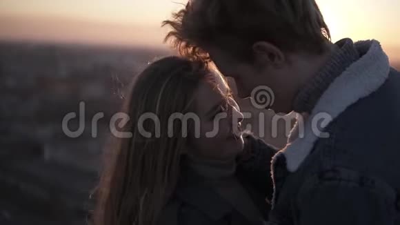 年轻的一对充满爱意的年轻夫妇在风中站立时享受着阳光照射下的浪漫吻视频的预览图