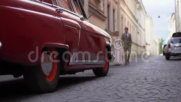 年轻的新婚夫妇在城市里散步新郎新娘在城市的路上开着老式复古车苏联红俄罗斯视频的预览图