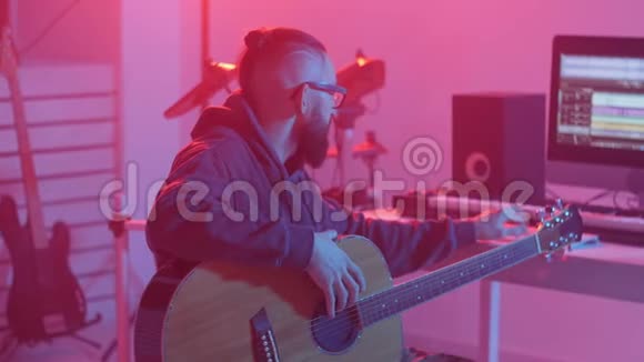 爱好和音乐的概念一个留胡子的年轻人在一家音乐工作室弹吉他视频的预览图