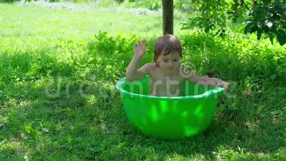 微笑的婴儿洗澡两只手在小浴缸里飞溅视频的预览图
