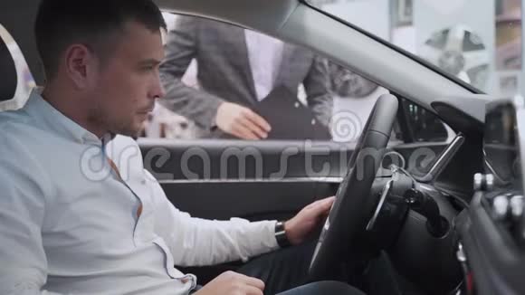 男士在汽车经销店与销售员交谈同时选择一种新的汽车通讯积极帮助视频的预览图