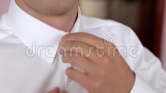 穿着衬衫的男人在家里打扮和调整领带会成功的视频的预览图
