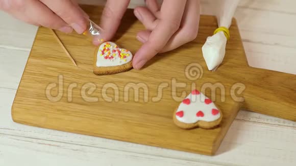 用糖霜装饰姜饼的过程女人的双手为情人节装饰心形饼干视频的预览图
