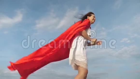 滑稽的超级英雄女孩穿着红色斗篷跑着笑斗篷在风中飘扬开朗的年轻女人扮演超级英雄视频的预览图