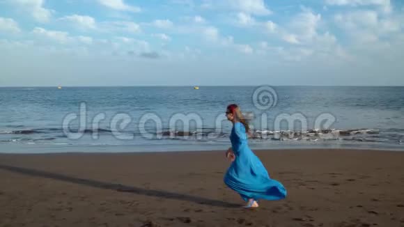 穿着漂亮蓝色裙子的女人在黑色的火山海滩上奔跑视频的预览图