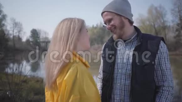 描绘了一对年轻可爱的夫妇在城外河边散步穿着黄色雨衣的金发美女视频的预览图