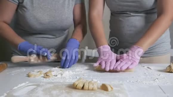 妈妈和怀孕的女儿在家厨房准备饺子和糕点的面团视频的预览图