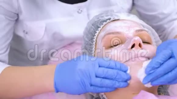 美容师用棉垫从面膜洗脸特写的脸视频的预览图