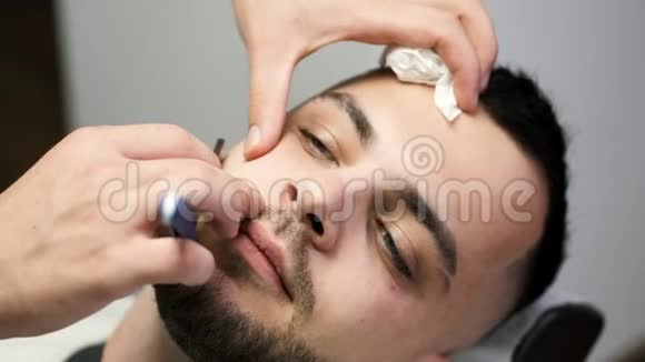 理发店理发师剪客人胡须过程的特写视频的预览图