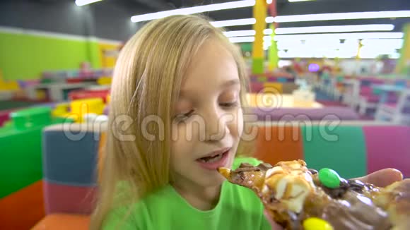 在娱乐中心吃披萨的女孩的特写镜头视频的预览图