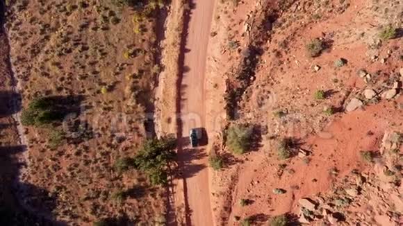黑暗的SUV在尘土飞扬的道路上行驶在阳光明媚的日子穿过一个红色的沙漠视频的预览图