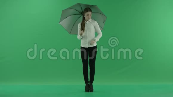 一个体贴的女人正在等待检查她的手表站在绿色屏幕上的伞她穿着正装视频的预览图