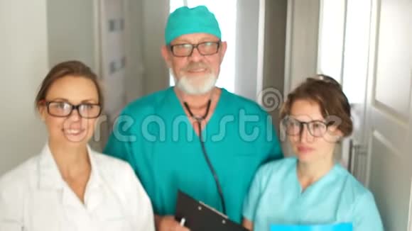 诊所里一队穿绿色外套的医生年轻的治疗师和他们的馆长一位老年男性医生的画像视频的预览图