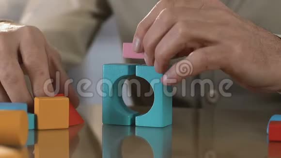 老人用颤抖的双手制作彩色木块的房子康复中心视频的预览图