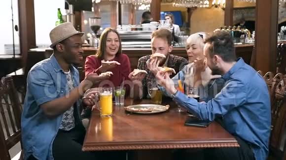 五个年轻时髦的朋友在时尚的酒吧和酒吧里拥抱着比萨饼视频的预览图