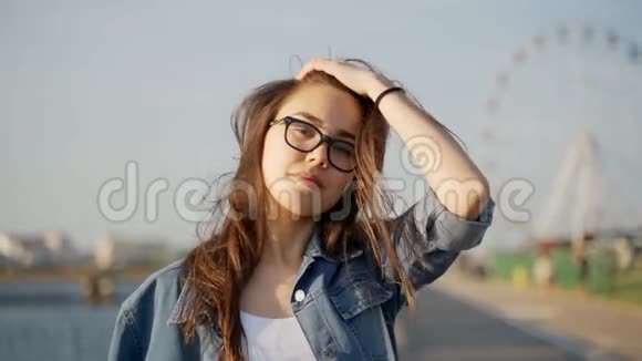 戴眼镜的漂亮年轻女孩穿过城市环顾四周戴眼镜的女孩的肖像慢动作视频的预览图