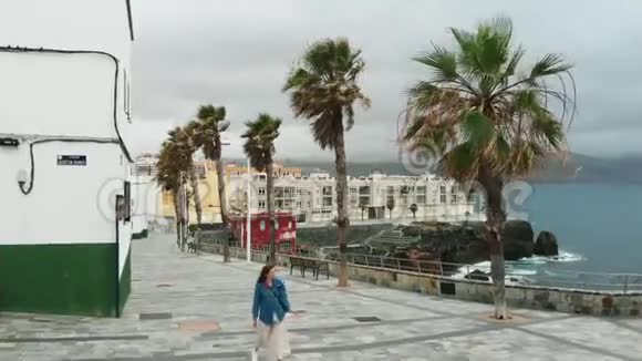 神圣的电影拍摄一个女孩走过一个废弃的西班牙城市沿着海岸在大风中视频的预览图