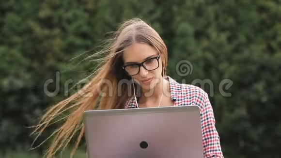 女孩在公园里用笔记本电脑视频的预览图