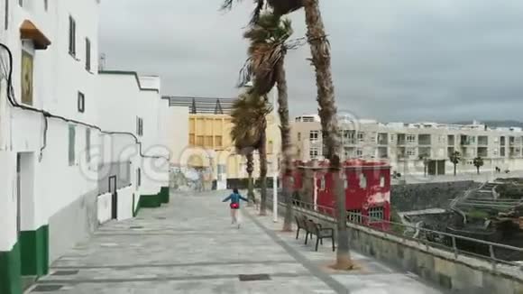 空中观景无人驾驶飞机飞过一个女孩她在飓风风中沿着一块古董瓷砖行走靠近一个小海湾视频的预览图