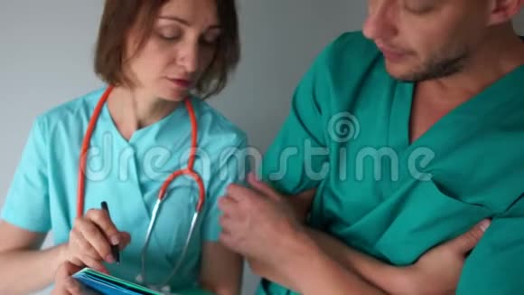 医务同事在实习中讨论工作问题穿绿色医疗间外套的男女医生视频的预览图