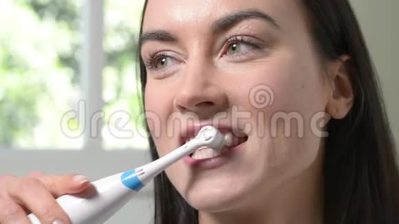 浴室里用电动牙刷刷牙的女人视频的预览图