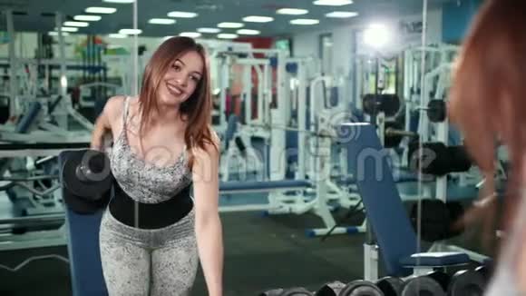 肌肉运动员妇女在健身房锻炼举重健身女孩在健身房用哑铃锻炼视频的预览图